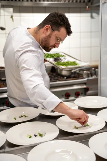 Szef kuchni wykańcza dania na kolację degustacyjną